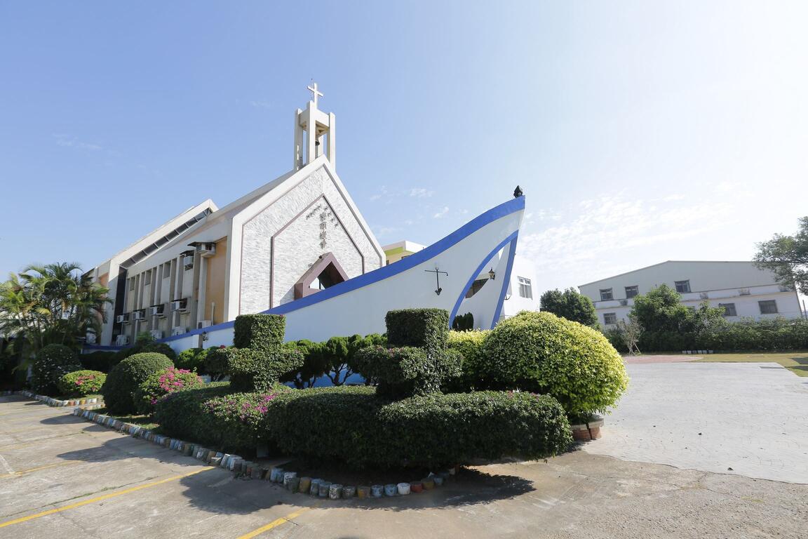 台中磐頂教會外觀,白色十字架建築結合藍白船形意象與庭園綠植,展現清新寧靜的宗教景觀。