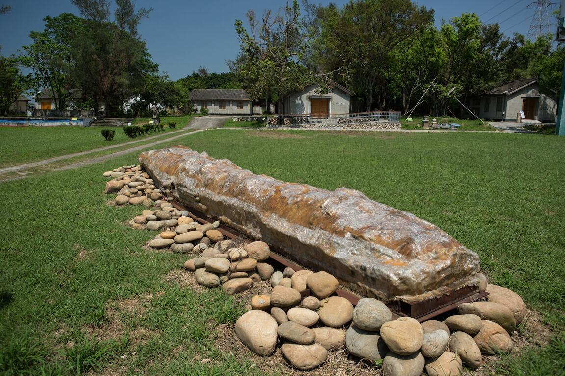 台中清水牛罵頭遺址文化園區草坪景觀,戶外展示長形石材遺構,後方可見老屋與綠樹。