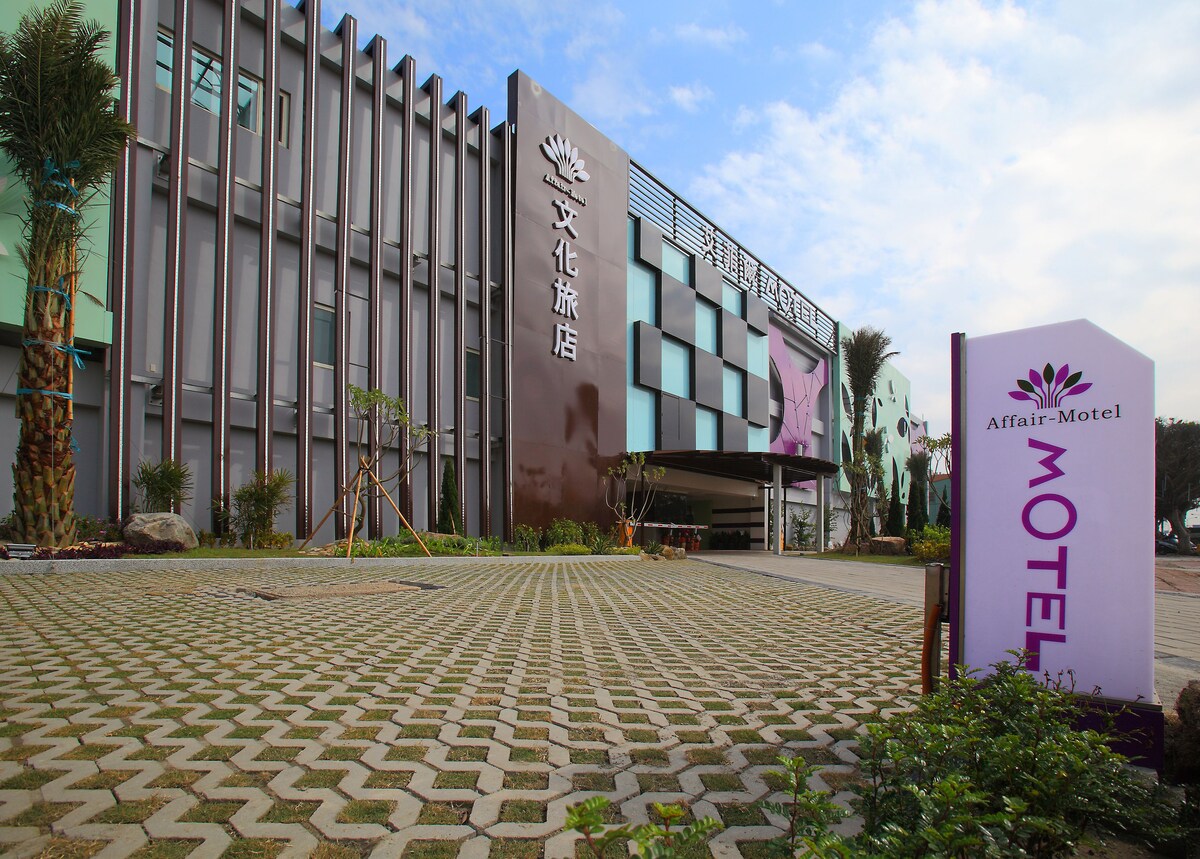 梧棲艾菲爾文化旅店建築外觀與車道入口,前方設有品牌招牌及綠化植栽。